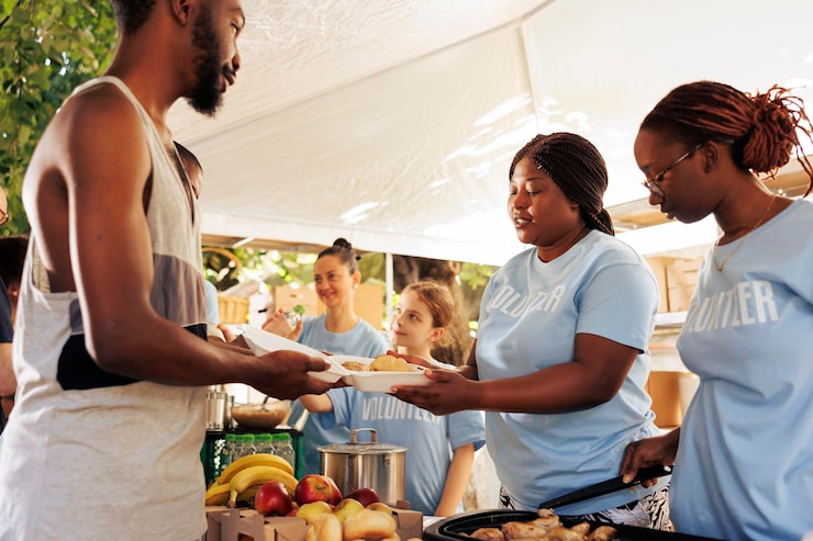multiethnic-female-volunteers-serving-free-food-homeless-man-outdoor-food-bank-non-profit-group-offers-humanitarian-aid-fosters-community-helping-hungry-less-privileged_482257-72623